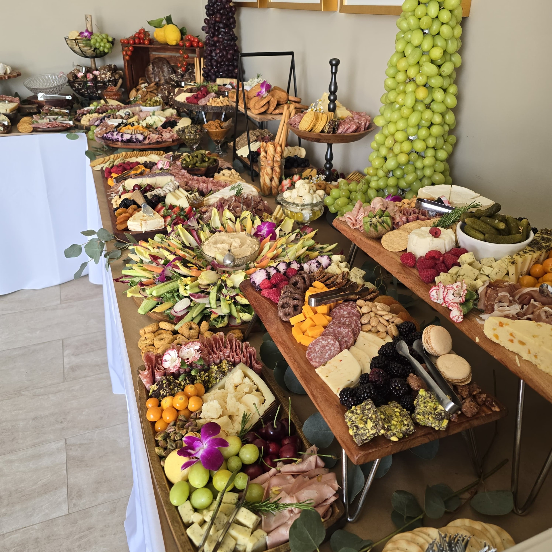 Large charcuterie and grazing table with cheeses, cured meats, fruit and crackers at an Orange County catered event